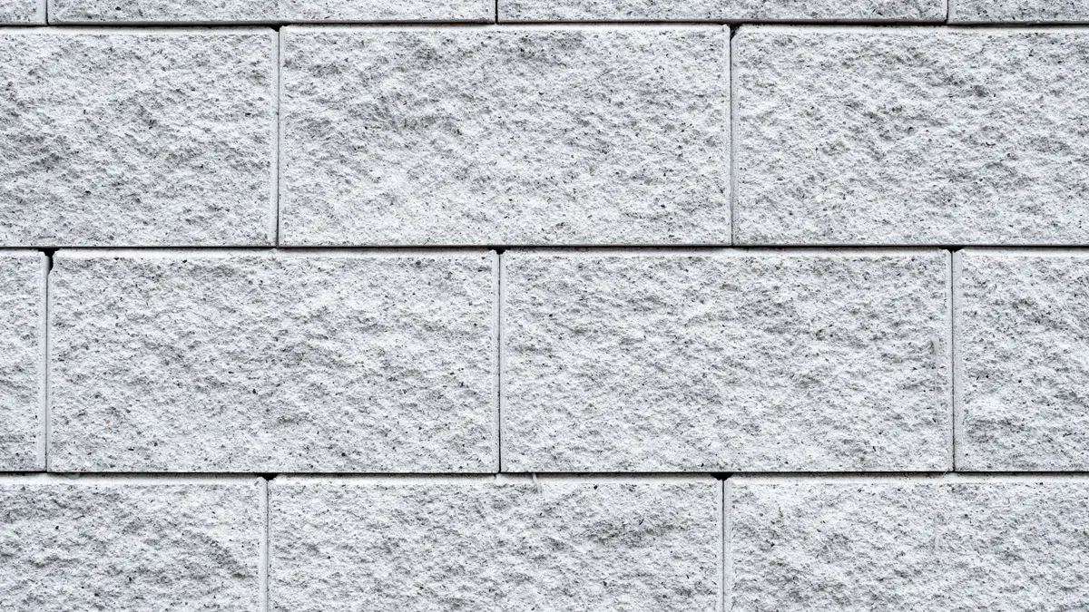 Close-up of a light gray split-face concrete masonry block wall