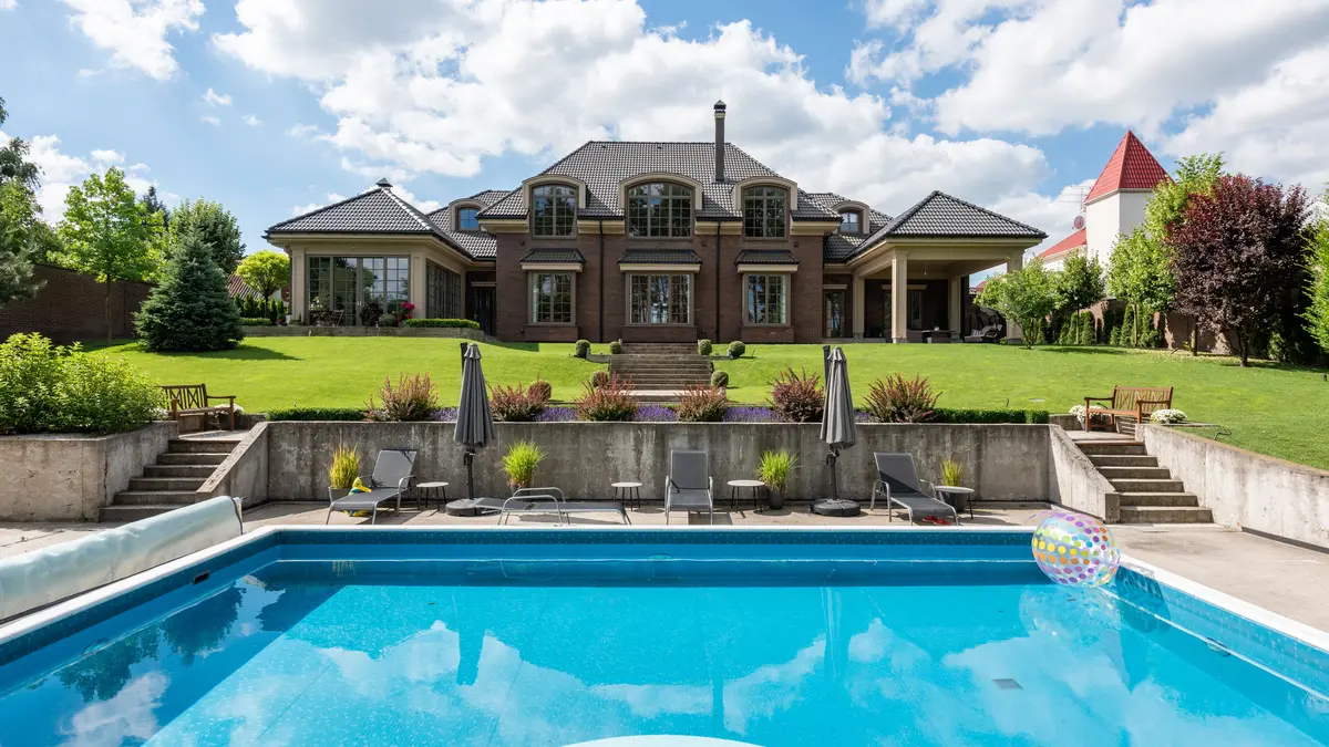 Backyard swimming pool with a light-colored concrete deck surrounding it
