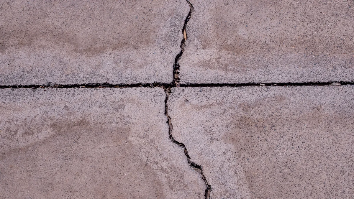 Cracked concrete driveway surface showing damage typical of freeze-thaw cycling before repair