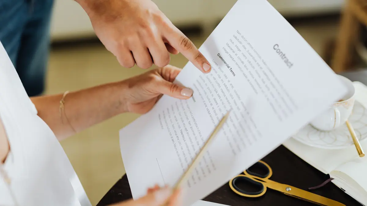 Two people reviewing and pointing at a printed contract on a table